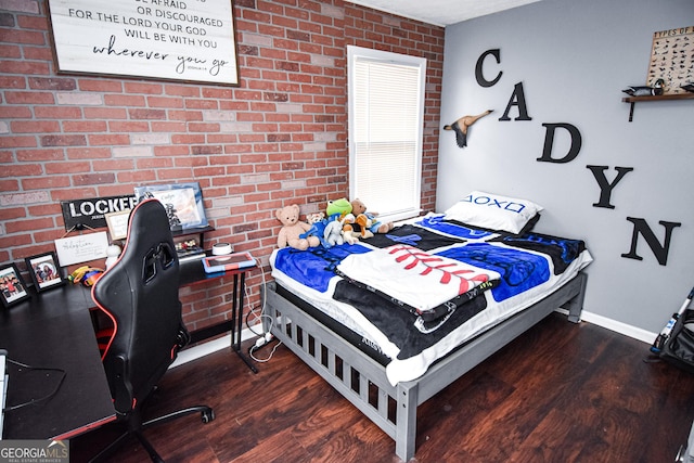 bedroom with baseboards, brick wall, and wood finished floors