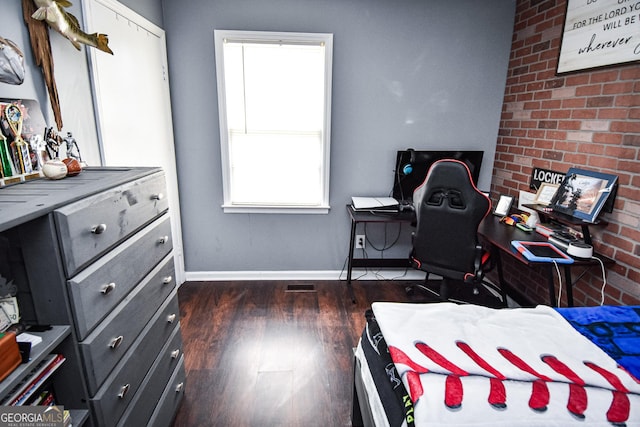 bedroom featuring brick wall, baseboards, and dark wood-style flooring