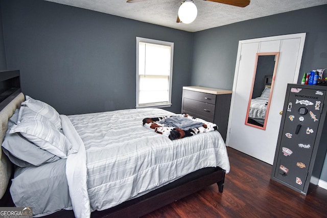 bedroom with a textured ceiling, dark wood-type flooring, and a ceiling fan