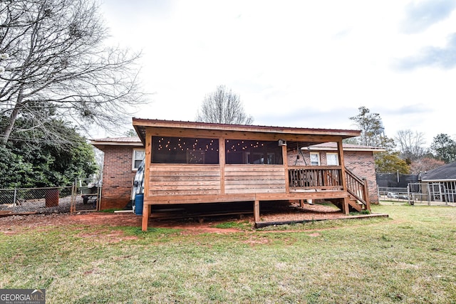 rear view of property featuring a yard, brick siding, fence, and a sunroom