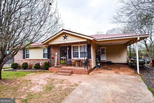 ranch-style house with metal roof, a porch, brick siding, concrete driveway, and a carport