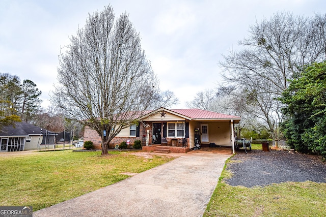 single story home featuring concrete driveway, metal roof, a trampoline, fence, and a front lawn