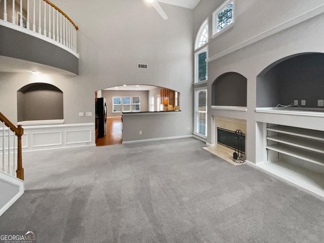 2708 Stockbridge Way, Dacula, GA 30019 - unfurnished living room featuring carpet flooring, built in shelves, a high end fireplace, a towering ceiling, and ceiling fan