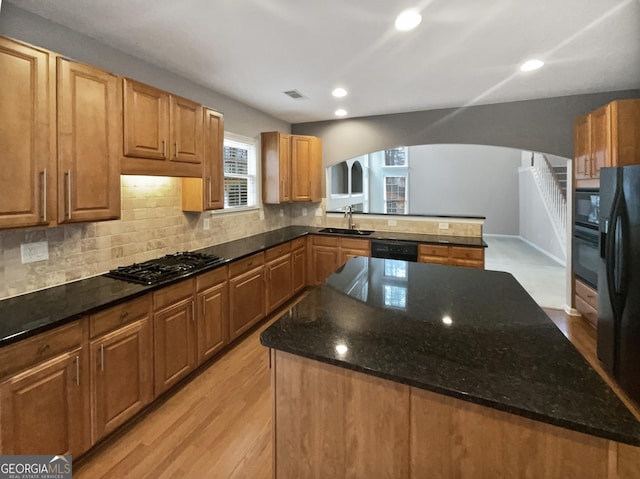 2708 Stockbridge Way, Dacula, GA 30019 - kitchen featuring arched walkways, black appliances, a center island, backsplash, and dark stone counters