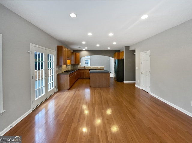 2708 Stockbridge Way, Dacula, GA 30019 - kitchen featuring freestanding refrigerator, arched walkways, dark countertops, wood finished floors, and brown cabinetry