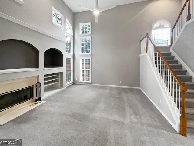 unfurnished living room featuring a wealth of natural light, baseboards, built in features, and a high end fireplace