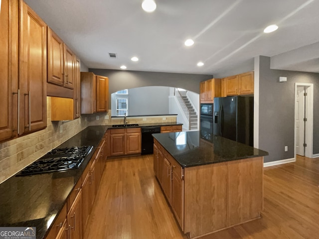 2708 Stockbridge Way, Dacula, GA 30019 - kitchen featuring black appliances, light wood finished floors, decorative backsplash, arched walkways, and a center island