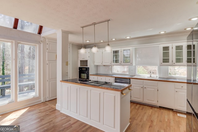 kitchen featuring glass insert cabinets, black appliances, white cabinetry, and light wood finished floors