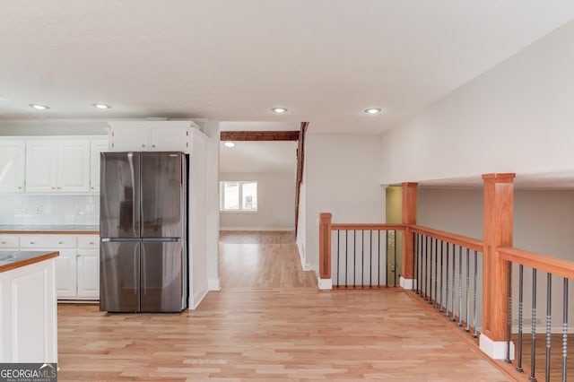 kitchen featuring tasteful backsplash, freestanding refrigerator, white cabinets, and light wood finished floors