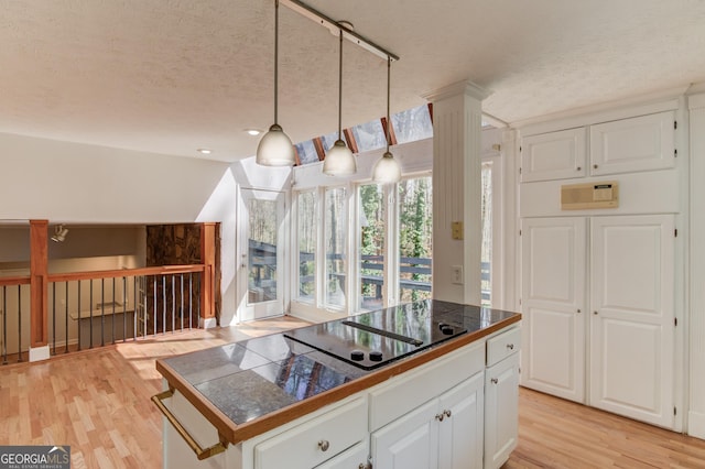 kitchen featuring a textured ceiling, black electric stovetop, white cabinets, and light wood-style floors