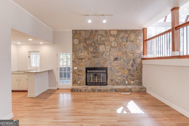 unfurnished living room with light wood-style floors, a fireplace, baseboards, and crown molding