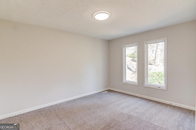 empty room featuring carpet floors, baseboards, and a textured ceiling