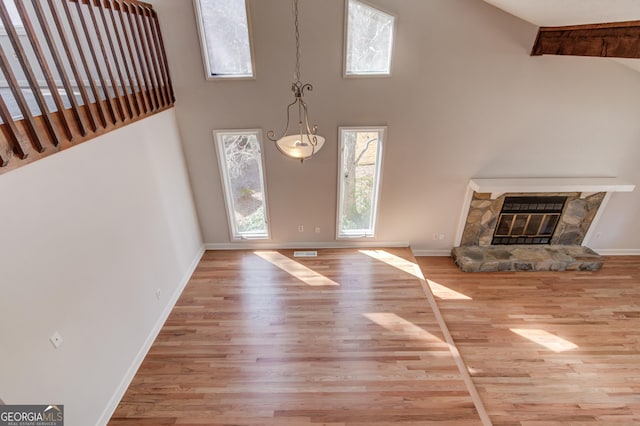 foyer with a fireplace, visible vents, a high ceiling, wood finished floors, and baseboards