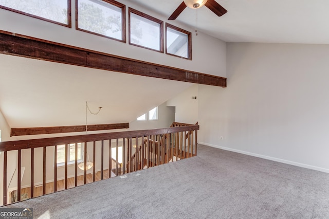 corridor featuring a wealth of natural light, baseboards, high vaulted ceiling, and carpet flooring