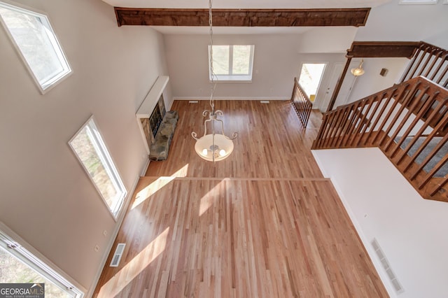 unfurnished living room with baseboards, a towering ceiling, stairway, wood finished floors, and beamed ceiling