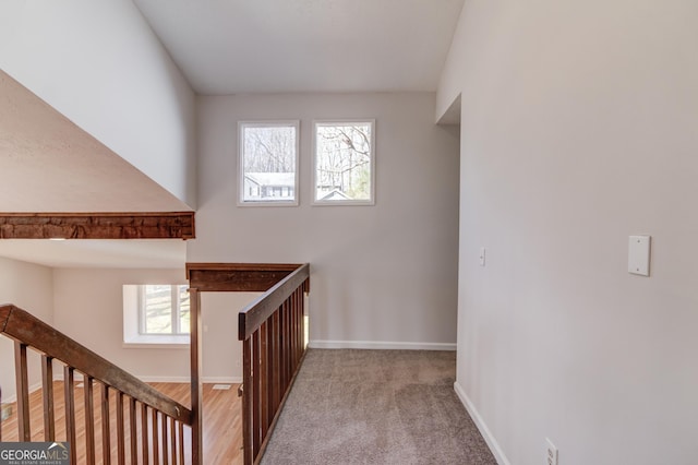 corridor with carpet floors, baseboards, and an upstairs landing