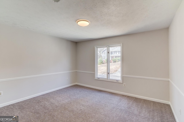 spare room featuring a textured ceiling, baseboards, and carpet flooring