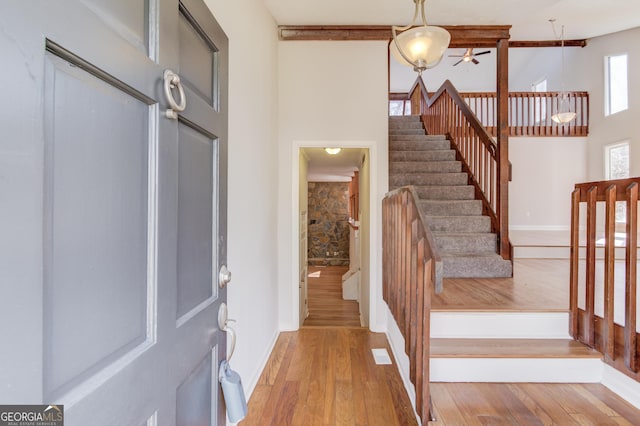 entryway with stairs, a high ceiling, wood finished floors, and baseboards