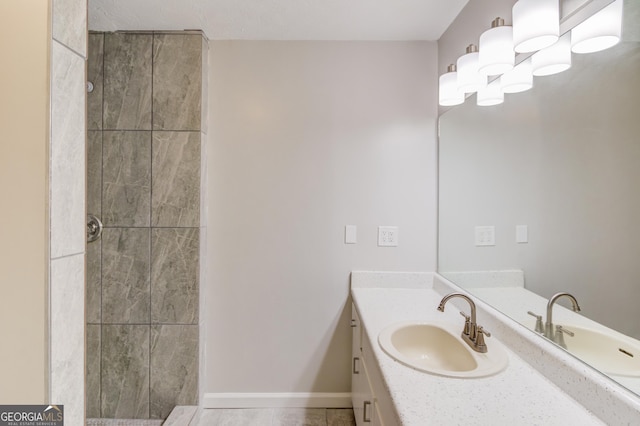 full bath with tiled shower, vanity, and baseboards