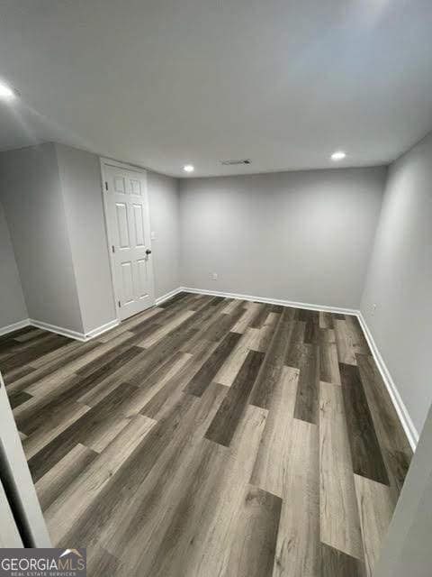 finished below grade area with baseboards, dark wood-type flooring, and recessed lighting