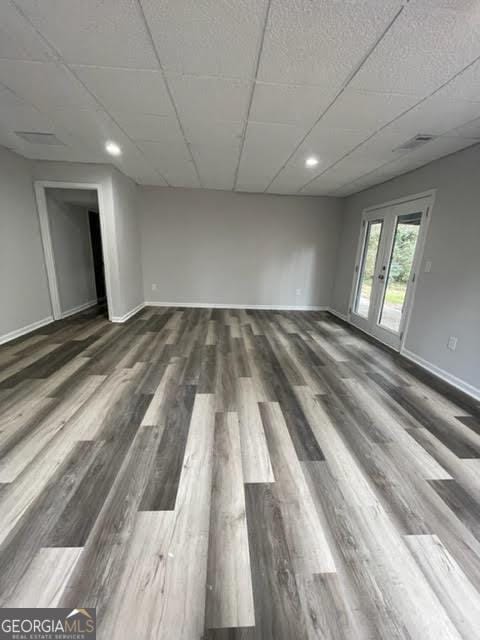 spare room featuring visible vents, baseboards, a drop ceiling, and wood finished floors