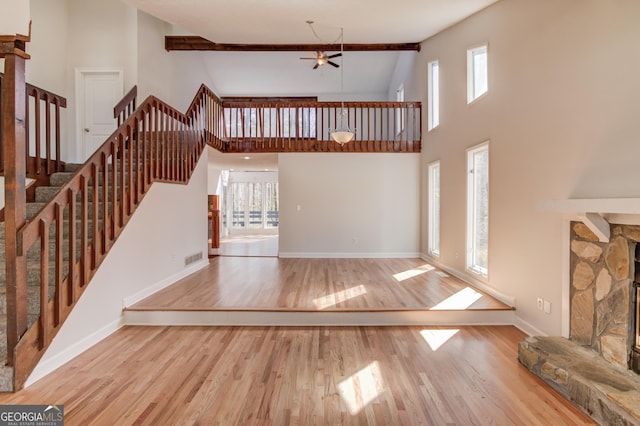 unfurnished living room with ceiling fan, a healthy amount of sunlight, a fireplace, and wood finished floors