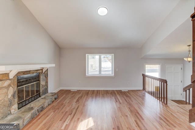 unfurnished living room with lofted ceiling, a fireplace, light wood-style flooring, and baseboards