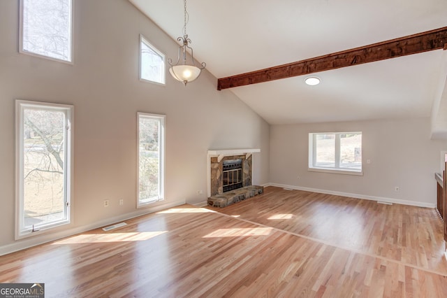 unfurnished living room featuring a healthy amount of sunlight, visible vents, a fireplace, and light wood finished floors