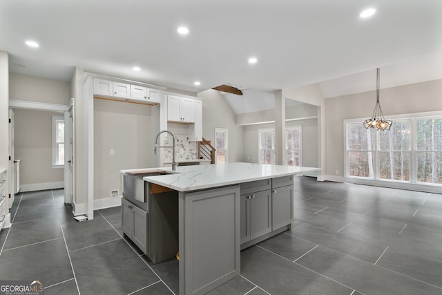 kitchen featuring a kitchen island with sink, recessed lighting, a sink, white cabinetry, and vaulted ceiling