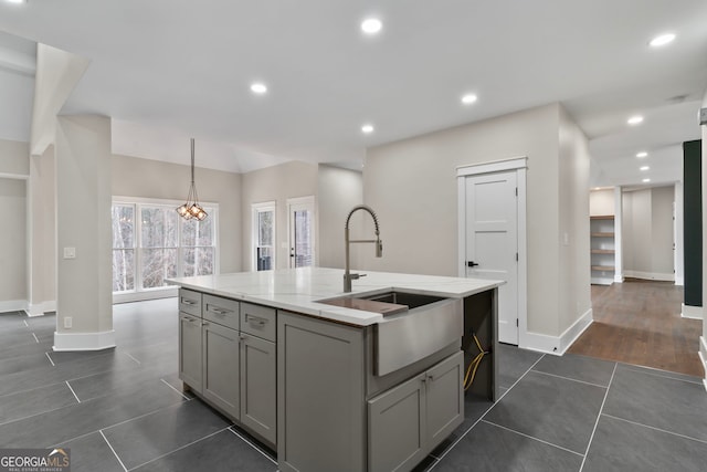 kitchen featuring a center island with sink, recessed lighting, gray cabinetry, a sink, and dark tile patterned floors