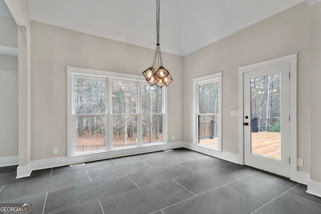 unfurnished dining area featuring baseboards, dark tile patterned floors, and an inviting chandelier