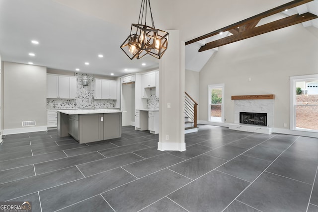 kitchen with tasteful backsplash, white cabinets, beamed ceiling, and visible vents