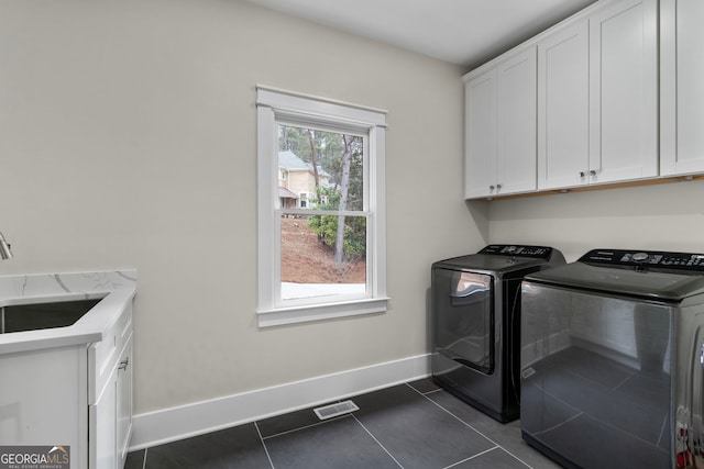 clothes washing area featuring dark tile patterned flooring, separate washer and dryer, a sink, baseboards, and cabinet space