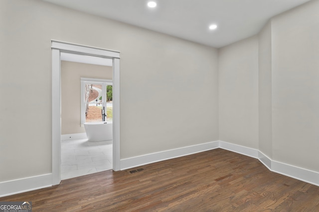 spare room featuring dark wood-style floors, baseboards, visible vents, and recessed lighting