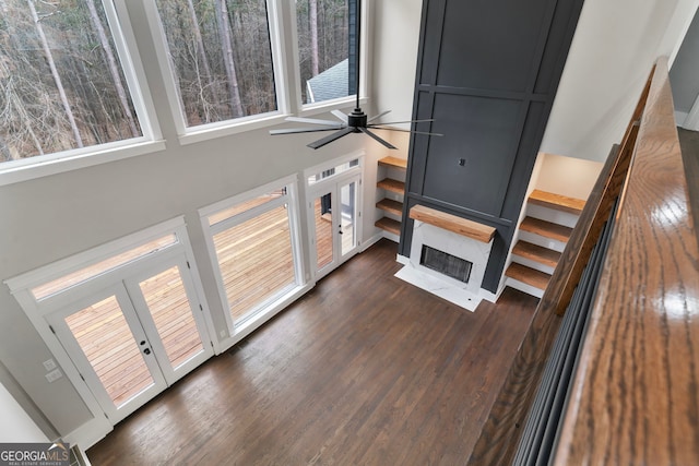 living area featuring ceiling fan, a high ceiling, a fireplace, and dark wood finished floors