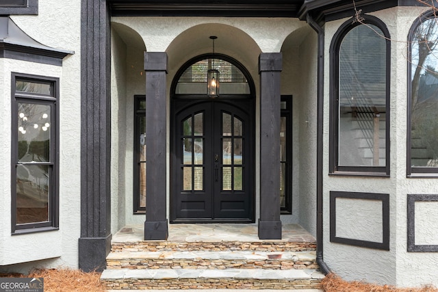 view of exterior entry featuring french doors and stucco siding