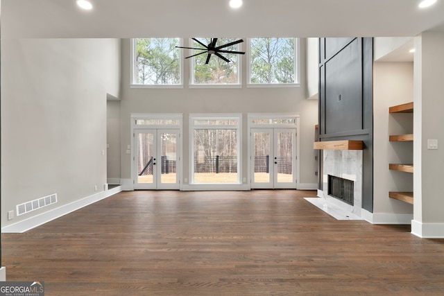 unfurnished living room with dark wood-style flooring, french doors, a premium fireplace, and visible vents