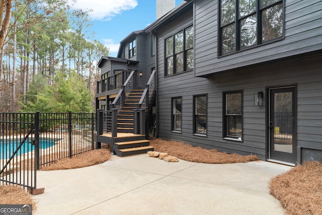 exterior space with a patio, stairway, a chimney, and a fenced in pool