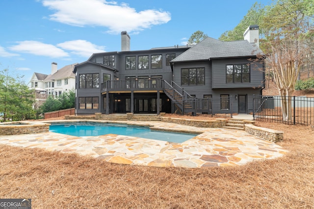 back of property featuring fence, a chimney, a wooden deck, and stairs