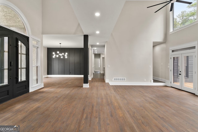 foyer entrance with visible vents, a towering ceiling, dark wood-style flooring, french doors, and ceiling fan with notable chandelier