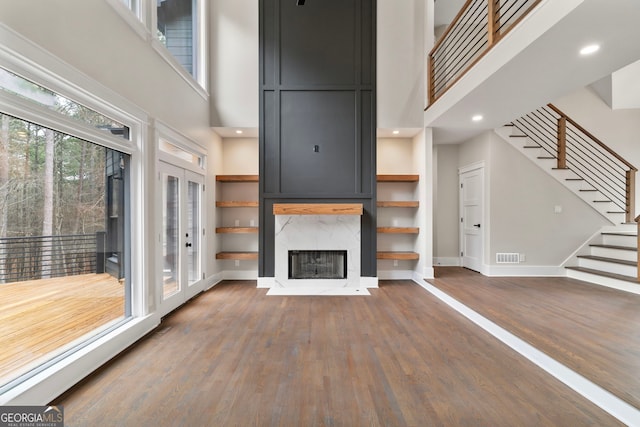 unfurnished living room with baseboards, visible vents, stairway, wood finished floors, and a fireplace