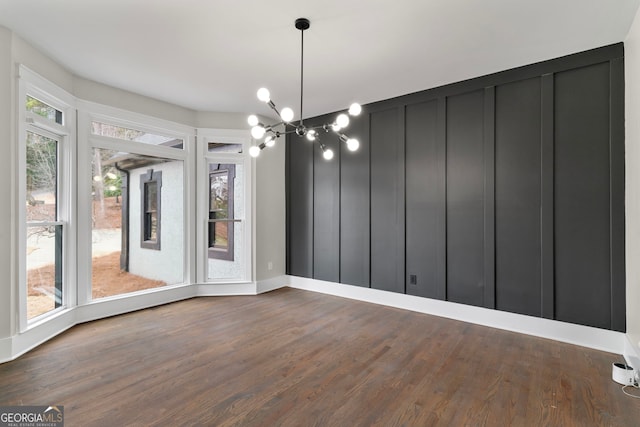 unfurnished dining area featuring dark wood finished floors and a notable chandelier