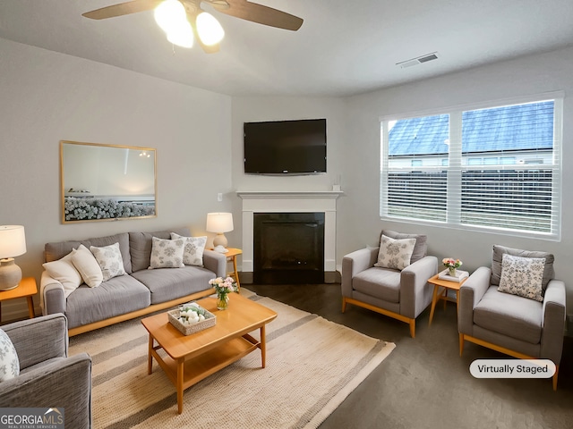 living area with a fireplace with flush hearth, visible vents, and ceiling fan