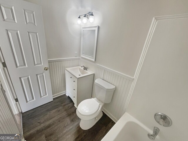 full bathroom featuring a wainscoted wall, wood finished floors, vanity, and toilet