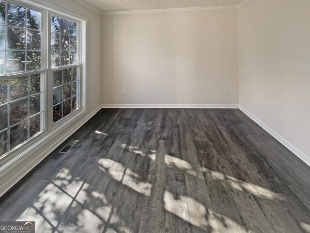 spare room featuring baseboards, visible vents, dark wood-style flooring, and crown molding