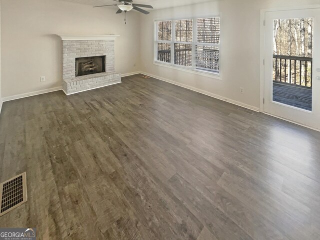 unfurnished living room featuring a healthy amount of sunlight, a fireplace, visible vents, and dark wood finished floors