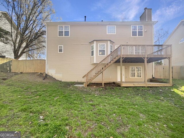 rear view of property with a fenced backyard, a chimney, stairs, a deck, and a yard