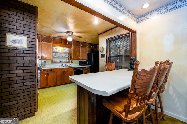 kitchen featuring brown cabinets, light floors, light countertops, freestanding refrigerator, and a peninsula