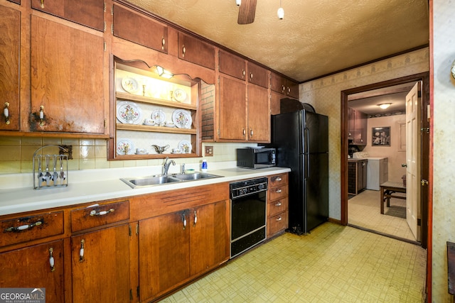 kitchen with washer and clothes dryer, light floors, light countertops, black appliances, and a sink