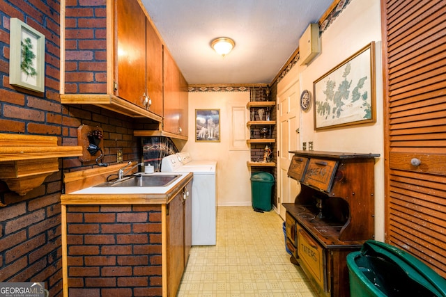 kitchen with washer and clothes dryer, brown cabinets, light countertops, light floors, and a sink